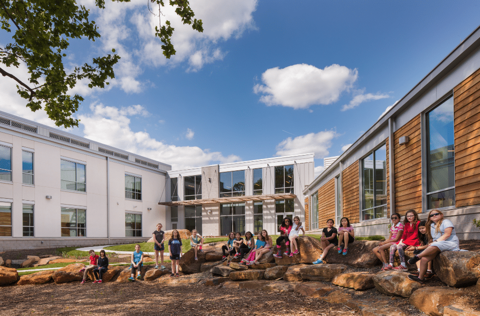 Elementary School Outdoor Classroom: Secluded Courtyard with Natural Rock Seating and Shaded by Local Trees