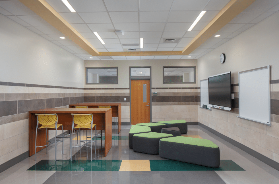A high school flexible classroom featuring a vibrant learning environment with colorful modular seating and a smart board for interactive lessons.